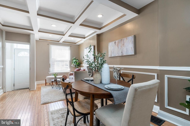 dining space featuring coffered ceiling, beamed ceiling, and light wood-type flooring