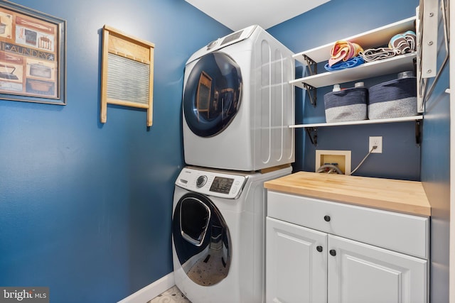 laundry room featuring cabinets and stacked washing maching and dryer