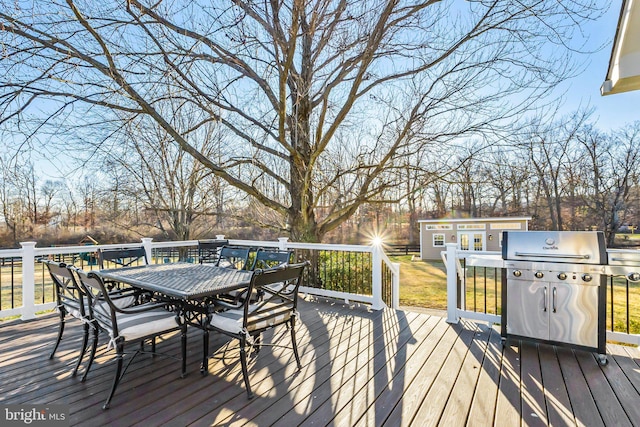 wooden deck with an outdoor structure and a grill