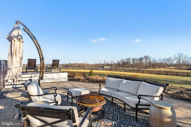 view of patio with a rural view and an outdoor living space with a fire pit