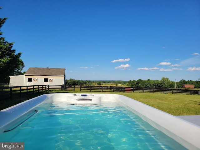 view of pool with a rural view, an outbuilding, and a lawn