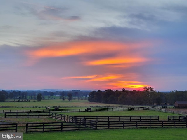 yard at dusk featuring a rural view