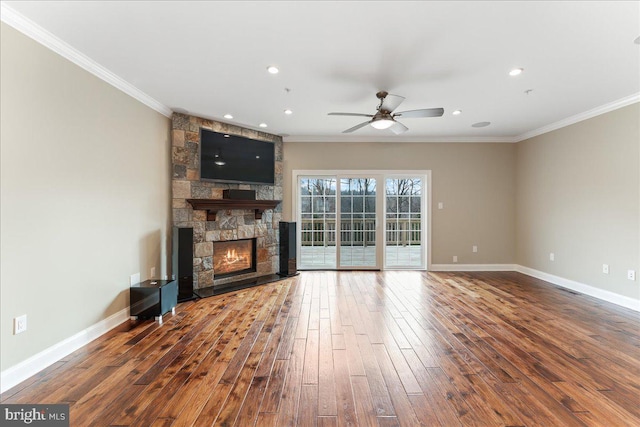 unfurnished living room with crown molding, a stone fireplace, dark wood-type flooring, and ceiling fan