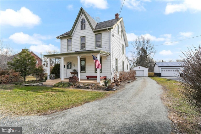 view of front of property with a porch, a garage, an outbuilding, and a front yard