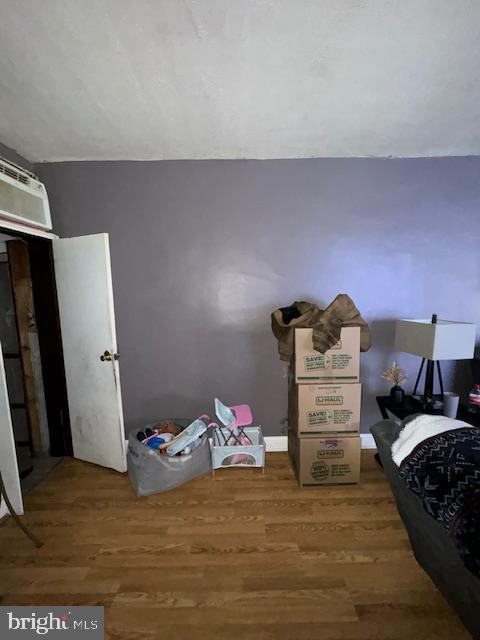 bedroom featuring wood-type flooring and a wall unit AC