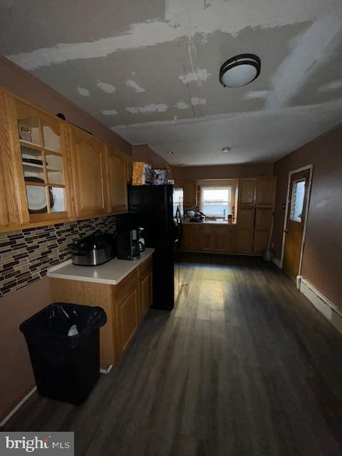 kitchen with black refrigerator, dark hardwood / wood-style floors, and decorative backsplash