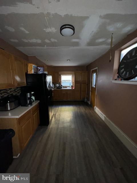 kitchen featuring tasteful backsplash, black refrigerator, and dark hardwood / wood-style floors