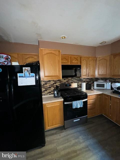 kitchen with decorative backsplash, black appliances, and dark hardwood / wood-style floors