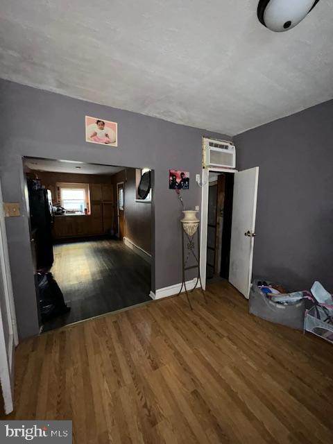 interior space with dark hardwood / wood-style floors and a wall unit AC