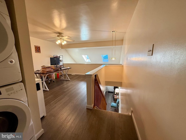 washroom with dark hardwood / wood-style flooring, a skylight, ceiling fan, and stacked washing maching and dryer