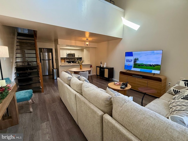 living room featuring a towering ceiling and dark hardwood / wood-style floors