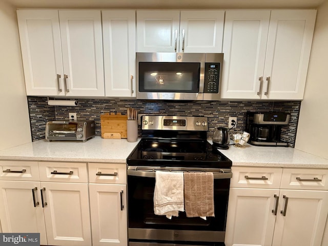 kitchen with light stone counters, white cabinets, and appliances with stainless steel finishes