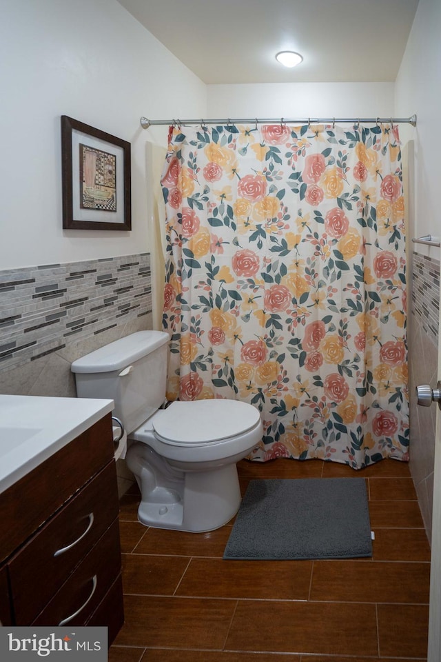 bathroom with vanity, tile walls, and toilet