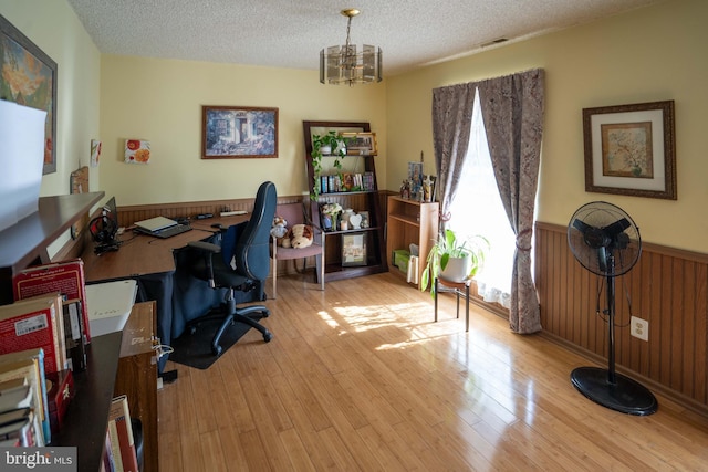 home office with an inviting chandelier, radiator, a textured ceiling, and light hardwood / wood-style flooring