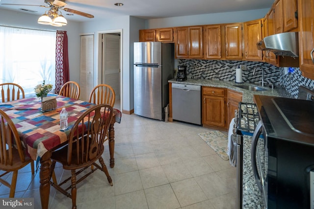 kitchen with appliances with stainless steel finishes, ventilation hood, tasteful backsplash, sink, and light stone counters