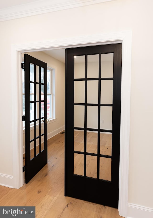 doorway to outside featuring ornamental molding, light hardwood / wood-style floors, and french doors