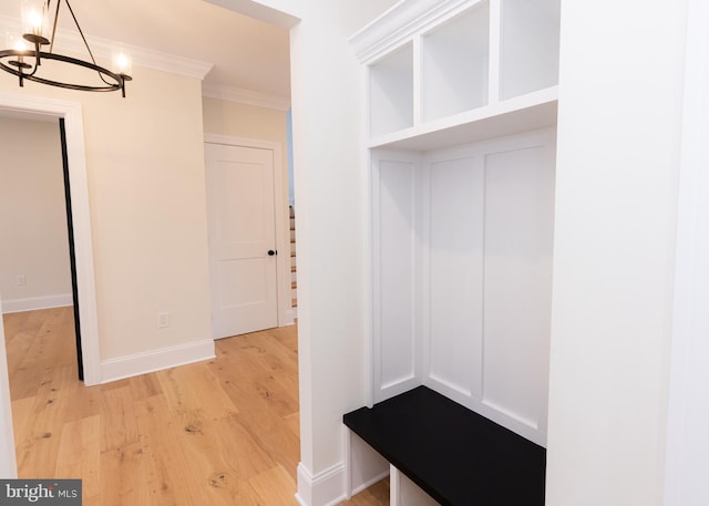 mudroom featuring crown molding, light hardwood / wood-style flooring, and a notable chandelier