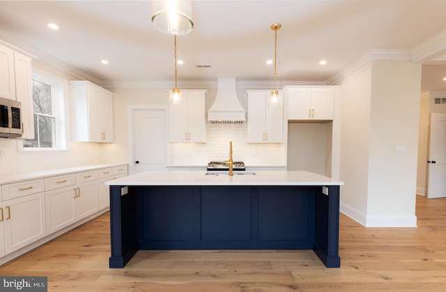 kitchen with white cabinetry, premium range hood, a kitchen island with sink, and pendant lighting