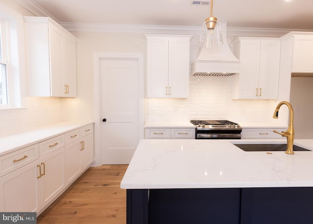 kitchen featuring hanging light fixtures, sink, white cabinets, and stainless steel stove