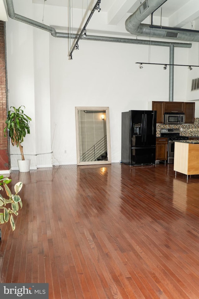 unfurnished living room with a high ceiling and hardwood / wood-style flooring