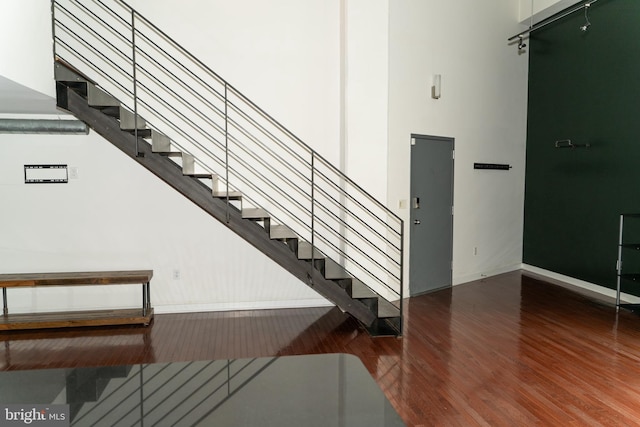 stairway featuring a high ceiling and wood-type flooring