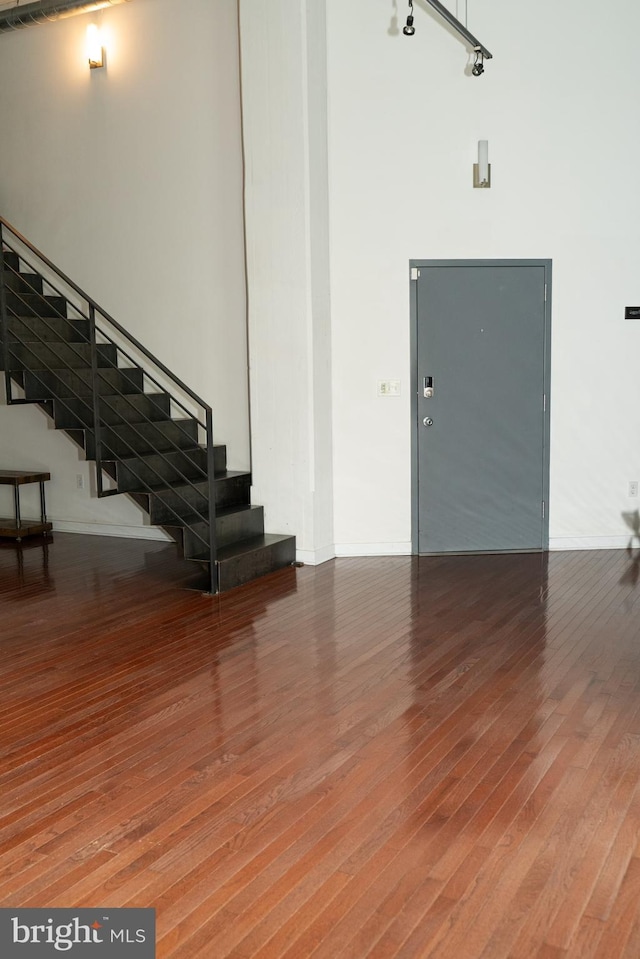 foyer featuring hardwood / wood-style floors, a towering ceiling, and track lighting