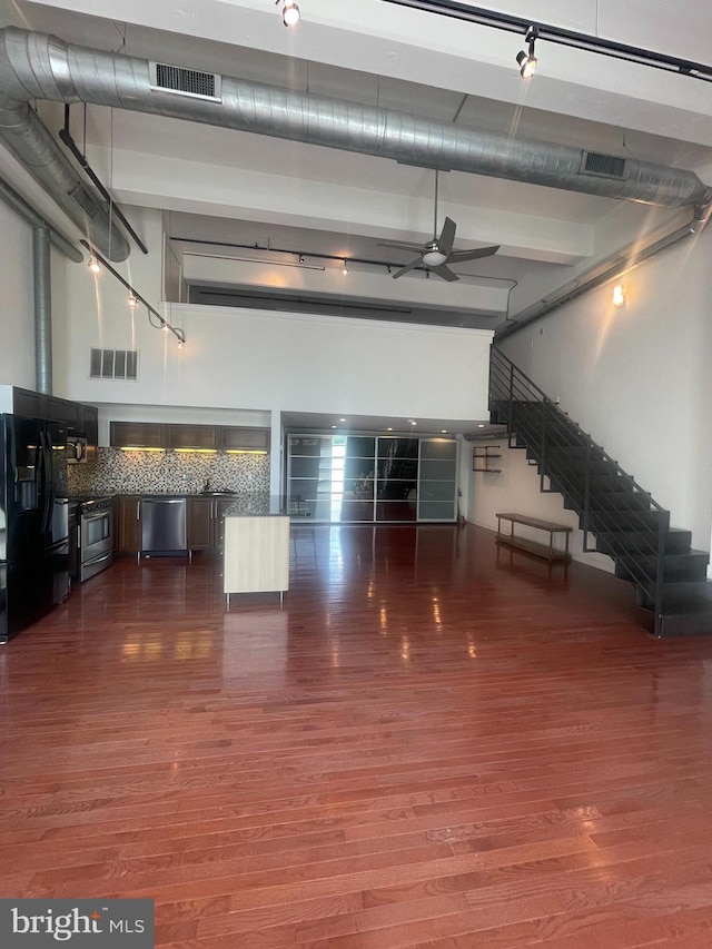 interior space with ceiling fan, a towering ceiling, and dark hardwood / wood-style floors