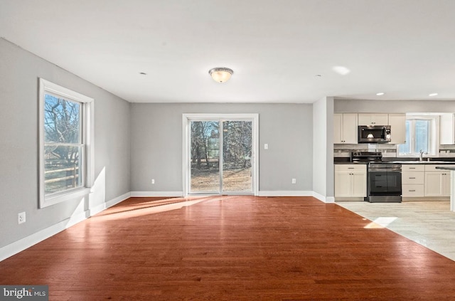 kitchen with stainless steel appliances, sink, light hardwood / wood-style flooring, and white cabinets