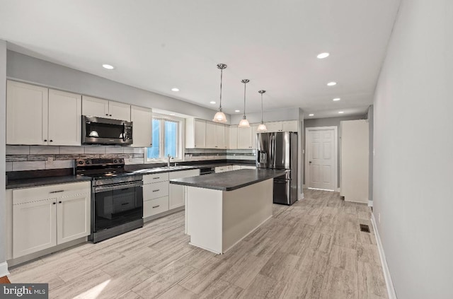 kitchen featuring sink, a center island, pendant lighting, stainless steel appliances, and white cabinets