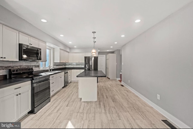 kitchen featuring decorative light fixtures, black appliances, white cabinets, and a kitchen island