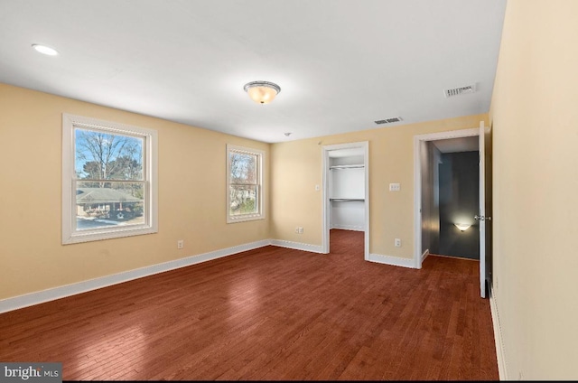 unfurnished bedroom featuring a closet, dark hardwood / wood-style floors, and a spacious closet