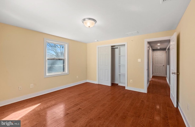 unfurnished bedroom with dark hardwood / wood-style floors and a closet