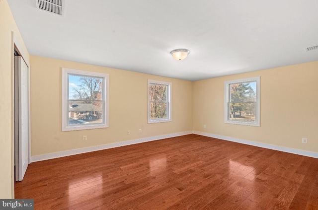 unfurnished room with hardwood / wood-style flooring and a healthy amount of sunlight