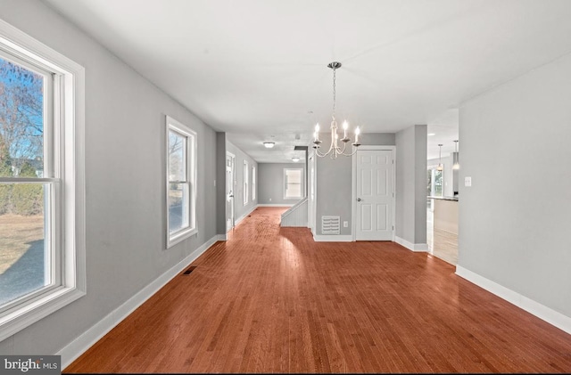 unfurnished dining area featuring an inviting chandelier and hardwood / wood-style floors