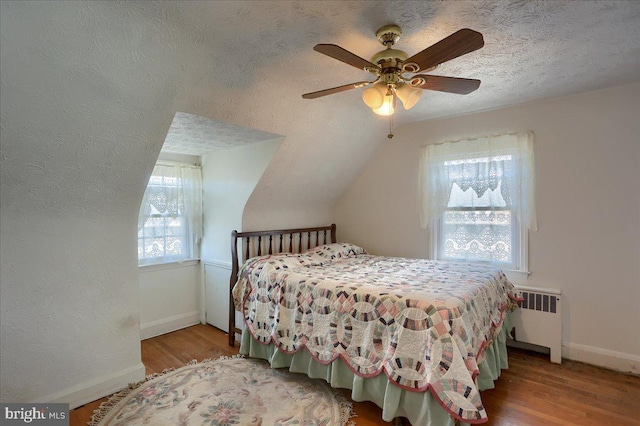 bedroom featuring radiator, light hardwood / wood-style floors, a textured ceiling, and ceiling fan