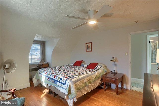 bedroom featuring ceiling fan, radiator heating unit, light hardwood / wood-style floors, and a textured ceiling