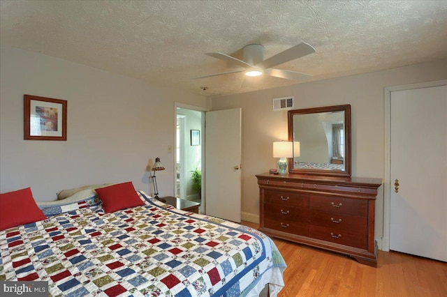 bedroom with ceiling fan, a textured ceiling, and light wood-type flooring