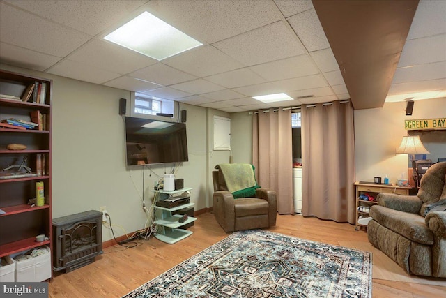 living room with hardwood / wood-style floors, a paneled ceiling, and a wood stove