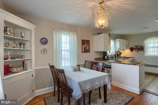 dining room featuring radiator, a notable chandelier, wood-type flooring, and sink