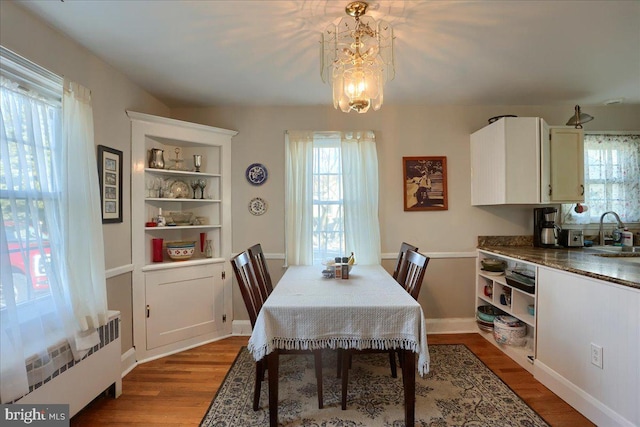 dining room featuring an inviting chandelier, radiator, sink, and light hardwood / wood-style flooring