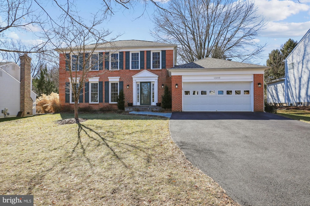 colonial house featuring a front yard and a garage