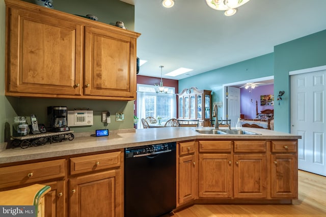 kitchen with a skylight, black dishwasher, sink, kitchen peninsula, and light hardwood / wood-style flooring