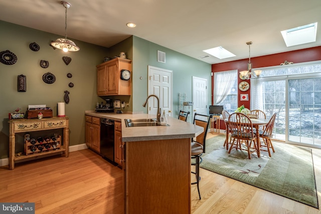 kitchen with sink, a skylight, black dishwasher, kitchen peninsula, and pendant lighting