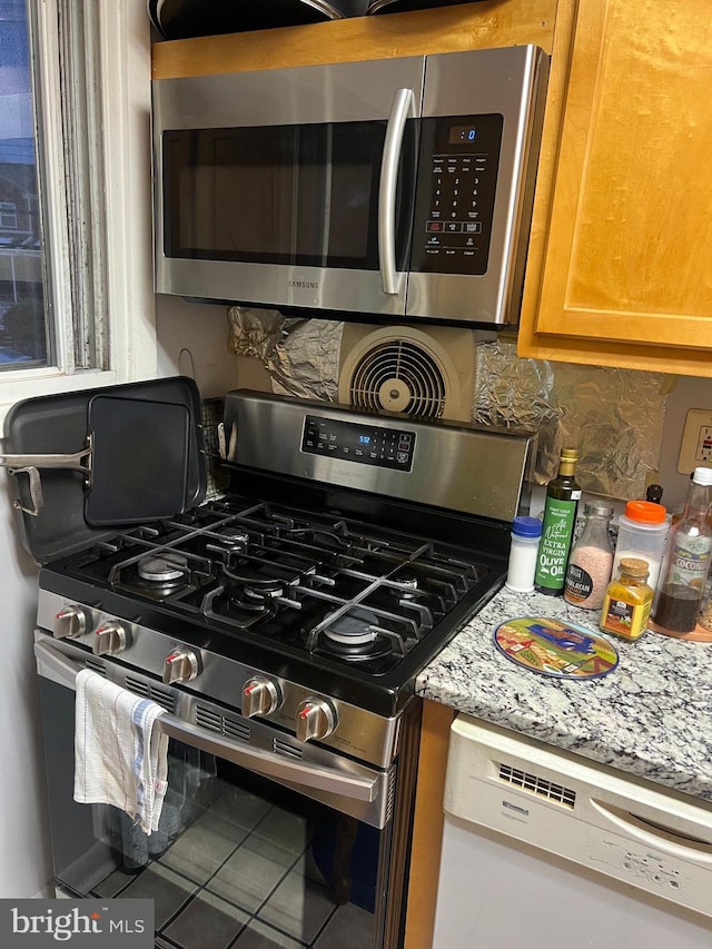 kitchen with light stone counters, stainless steel appliances, and decorative backsplash