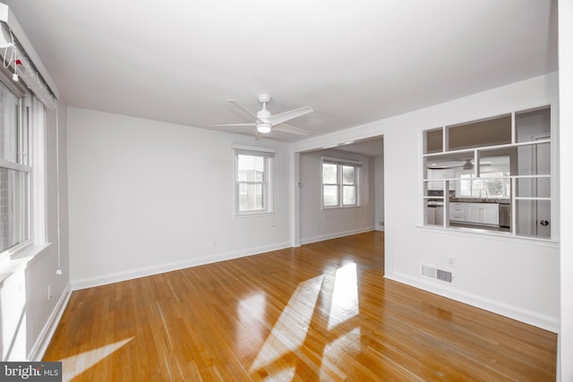 spare room featuring a ceiling fan, visible vents, baseboards, and wood finished floors