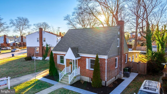 bungalow-style home featuring a residential view, a chimney, fence, a front lawn, and brick siding