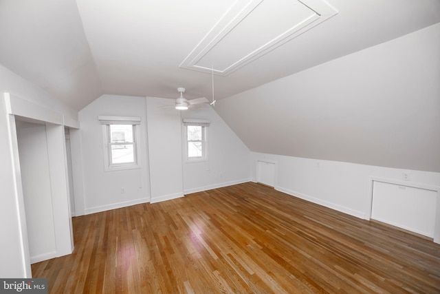 additional living space featuring attic access, vaulted ceiling, baseboards, and hardwood / wood-style flooring