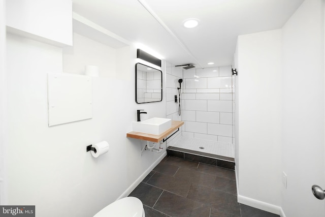 bathroom featuring toilet, a shower stall, baseboards, and a sink