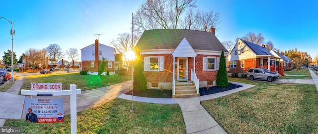 bungalow with a front yard, a chimney, and brick siding