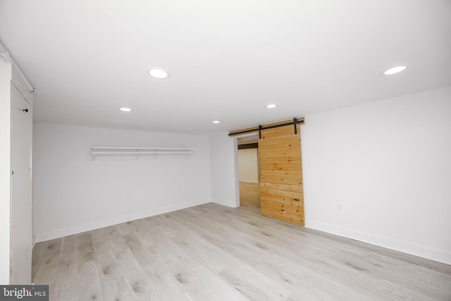 interior space featuring light wood-type flooring, a barn door, baseboards, and recessed lighting